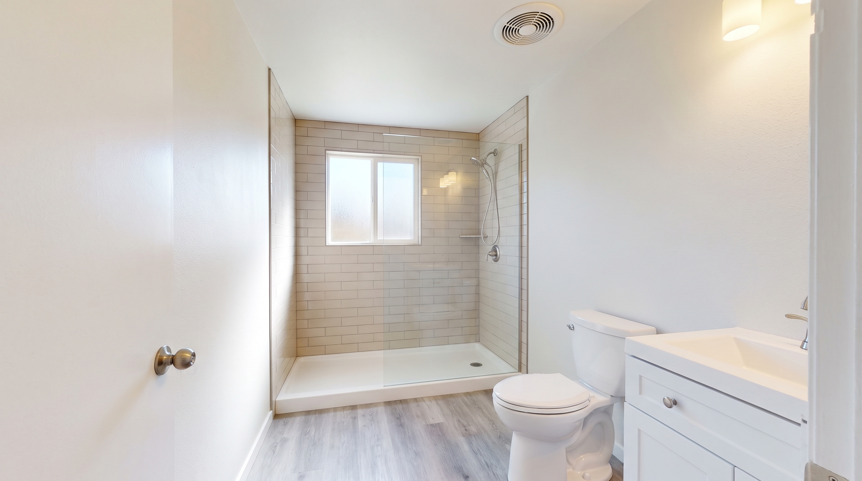 South Hill guest bathroom remodel with tiled walk-in shower, white vanity, and LVP flooring