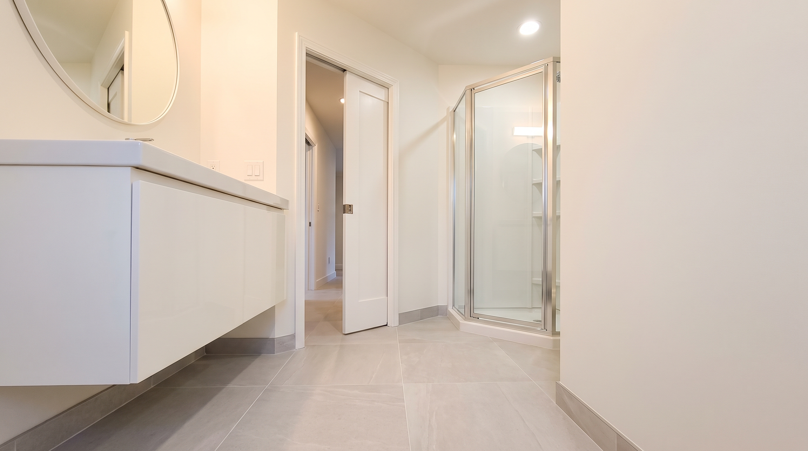 Small guest bathroom with wall-hung vanity, pocket door, and large-format tile flooring