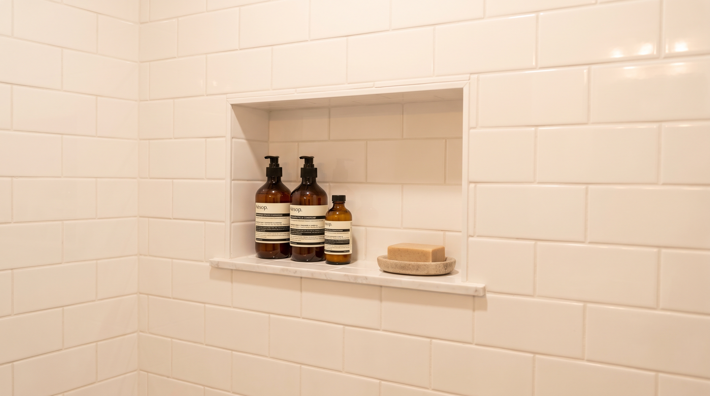 Recessed tile shower niche built into the wall holding shampoo bottles with no visible caddy