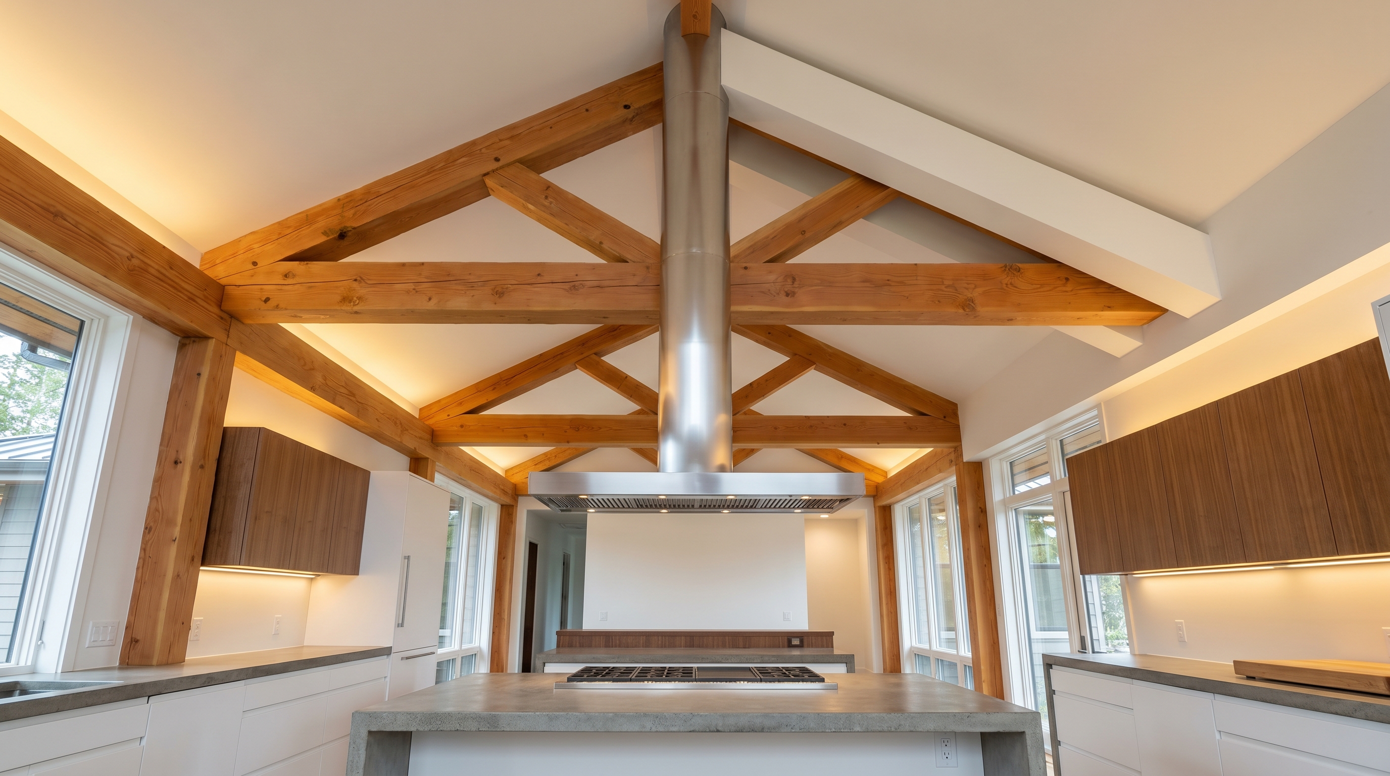 Island range hood with extended chimney column spanning a vaulted ceiling in a Pacific Northwest open-concept kitchen